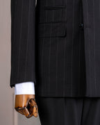 Close-up of a black stripe suit with a wooden hand wearing a white shirt cuff, featuring a 'French Cuff' label.