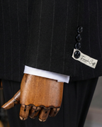 Close-up of a black pinstripe suit with a wooden hand wearing a white shirt cuff, featuring a 'French Cuff' label.